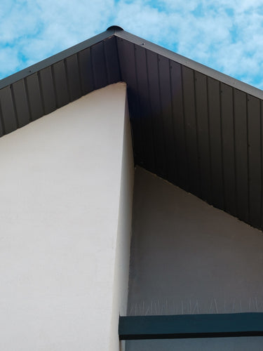 Hausfassade mit dunkler Dachuntersicht aus Holz, gestrichen mit Remmers Deckfarbe für langlebigen Wetterschutz.